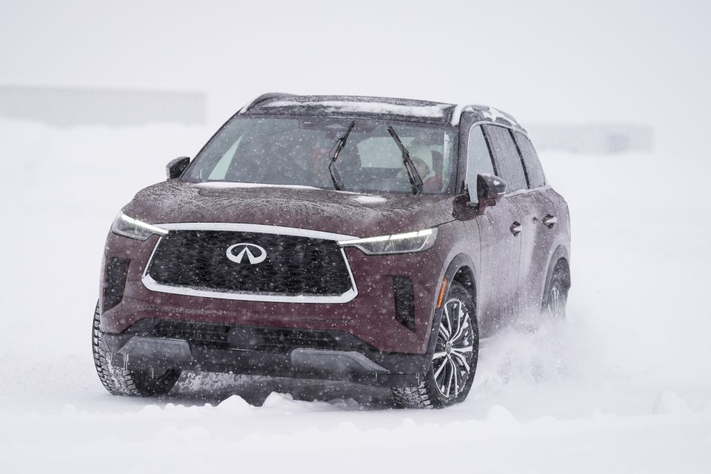 trendy latina driving the QX-60 in the snow